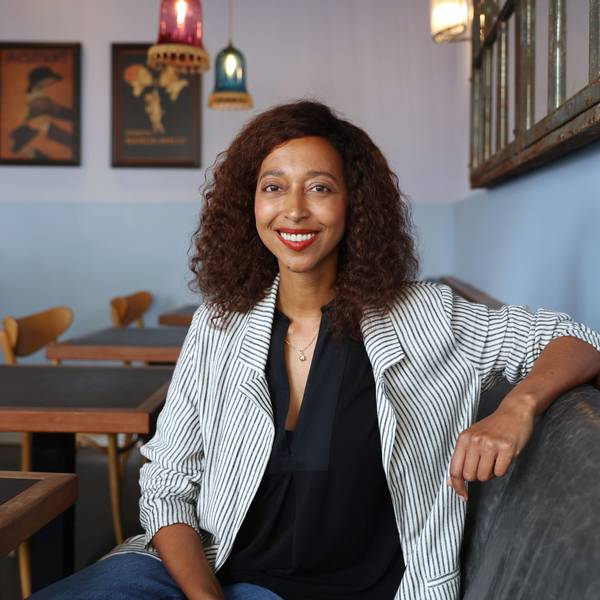 Melanie Raabe sitzt in einem Kölner Café. Sie trägt ein schwarzes Oberteil und einen gestreiften hellen Blazer.