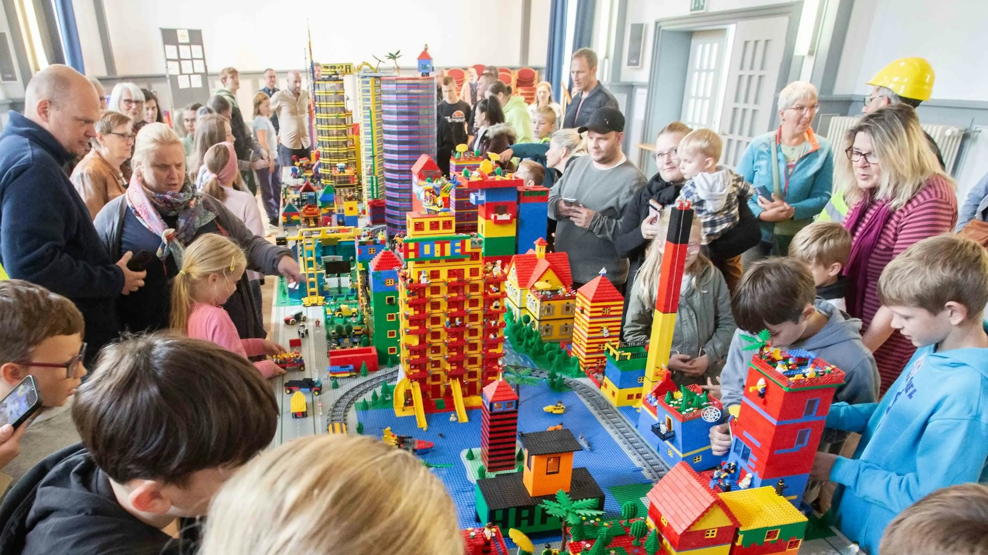 Viele Menschen stehen um einen Tisch, auf dem eine Modellstadt aus Lego-Steinen aufgebaut ist.