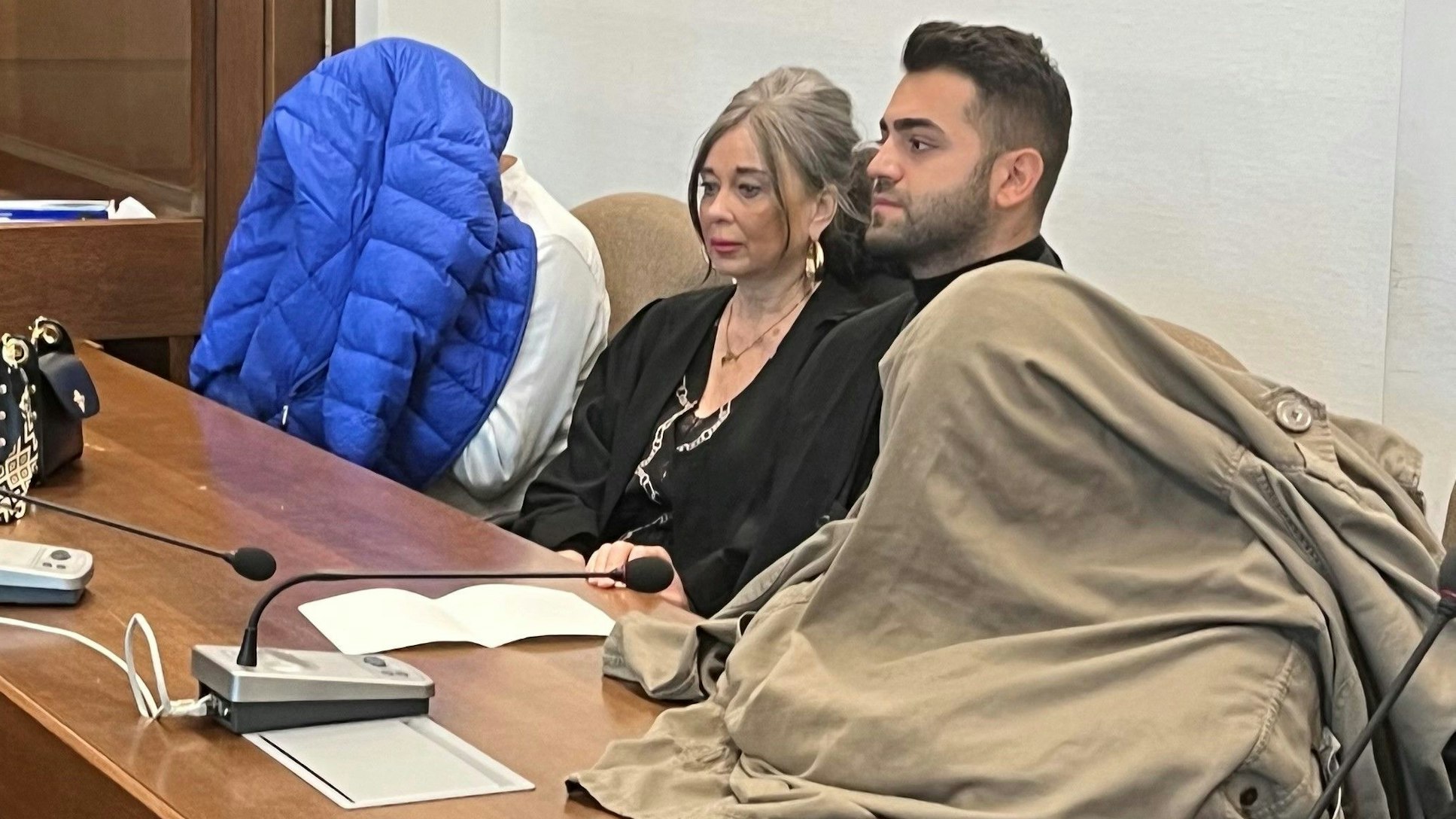 Die Angeklagten – mit den Verteidigern Petra Wunsch und Salih Kocak – verstecken ihre Gesichter vor den Pressekameras.