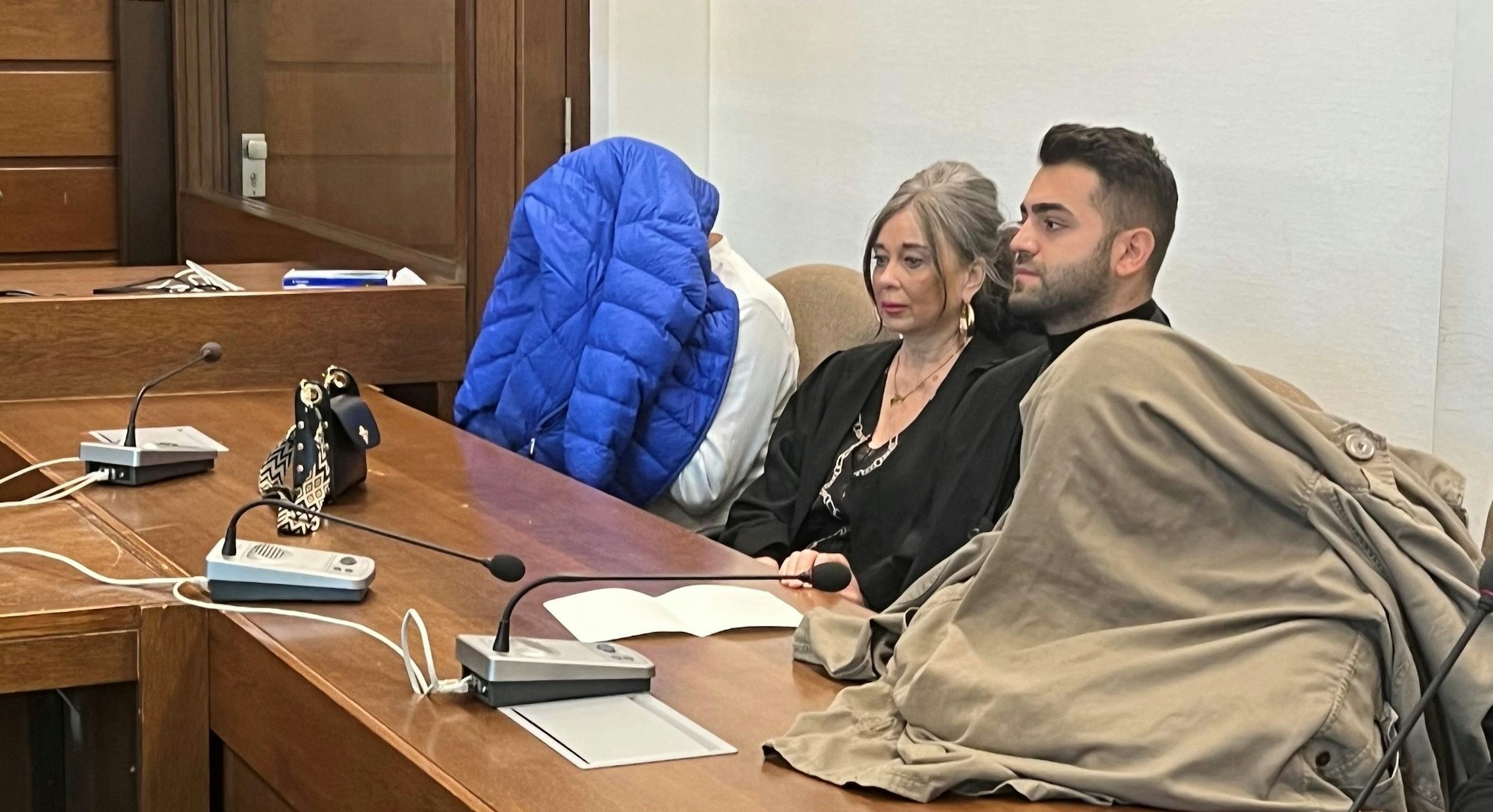 Die Angeklagte - mit den Verteidigern Petra Wunsch und Salih Kocak - verstecken ihre Gesichter vor den Pressekameras.