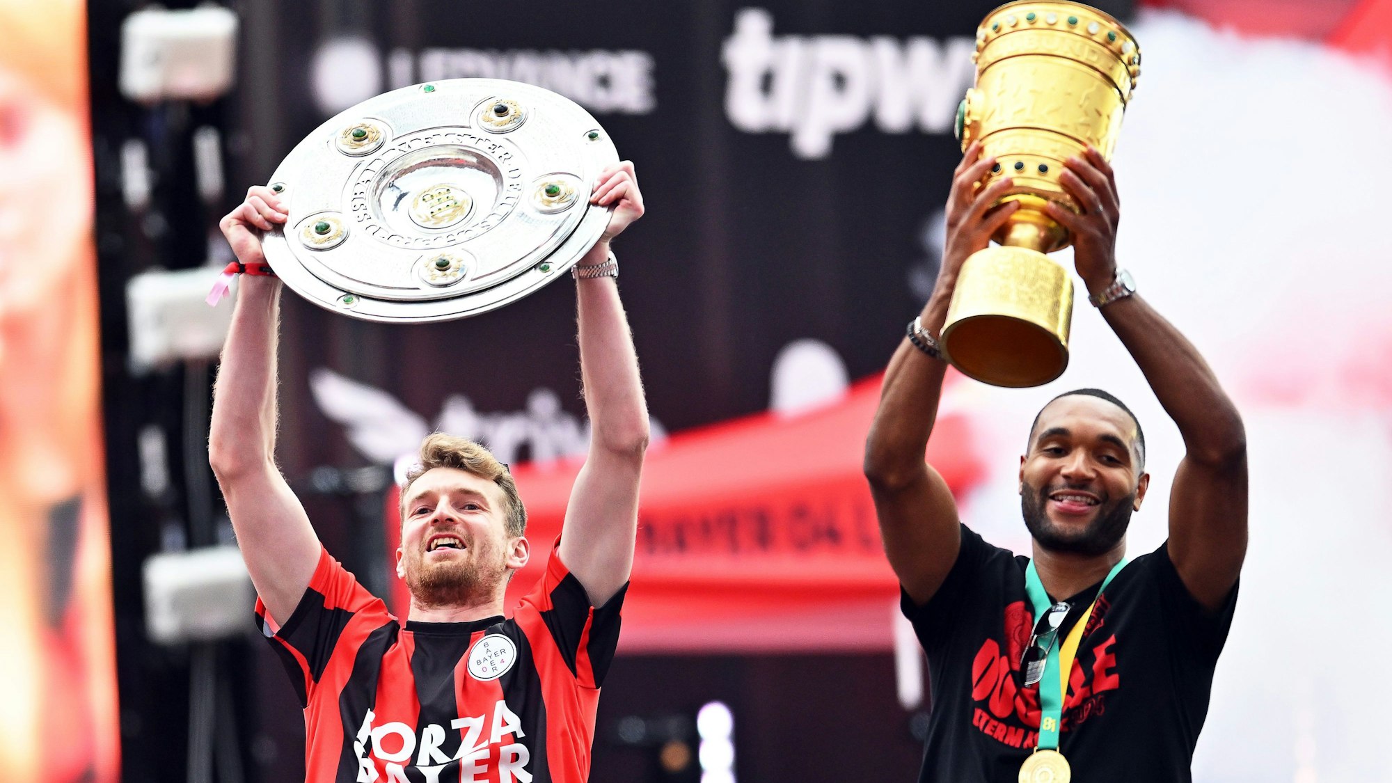 Leverkusens Torhüter Lukas Hradecky (l) und Jonathan Tah präsentieren bei der Meisterfeier in der BayArena die Meisterschale und den Pokal.