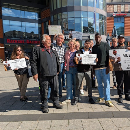 Eine Gruppe von Menschen steht mit Spruchtafeln vor dem Rathaus in Wiesdorf.
