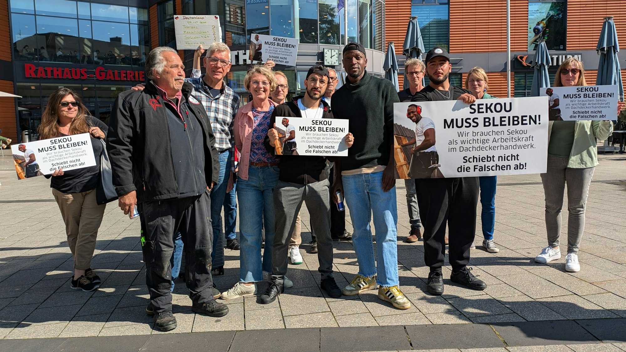 Eine Gruppe von Menschen steht mit Spruchtafeln vor dem Rathaus in Wiesdorf.