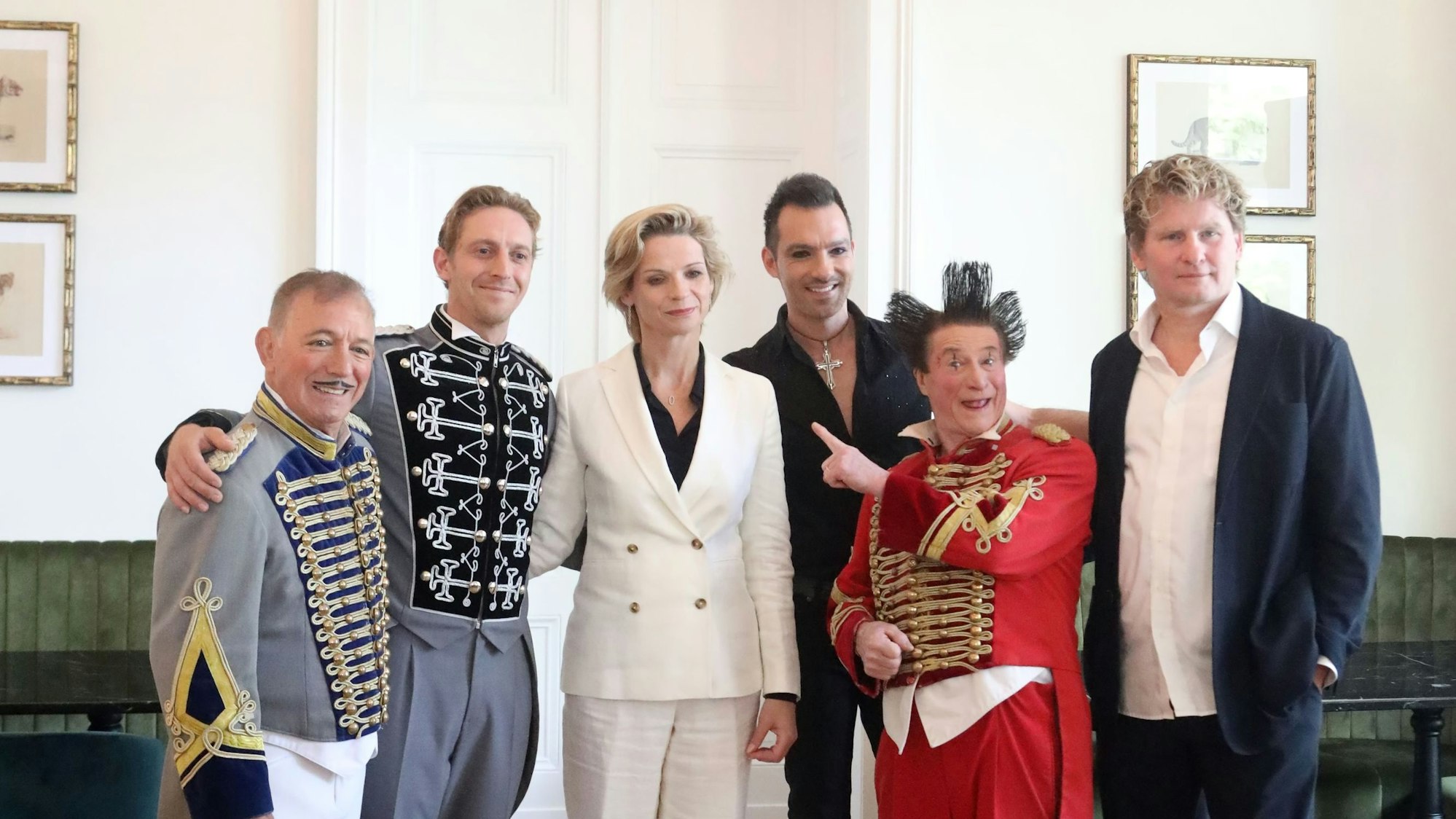 Daris Huesca, Nick Huesca, Katja Smitt, Vincent Vignaut, Gianni Huesca, Ilja Smitt in einem Saal, teilweise mit Clowns-Kleidung.