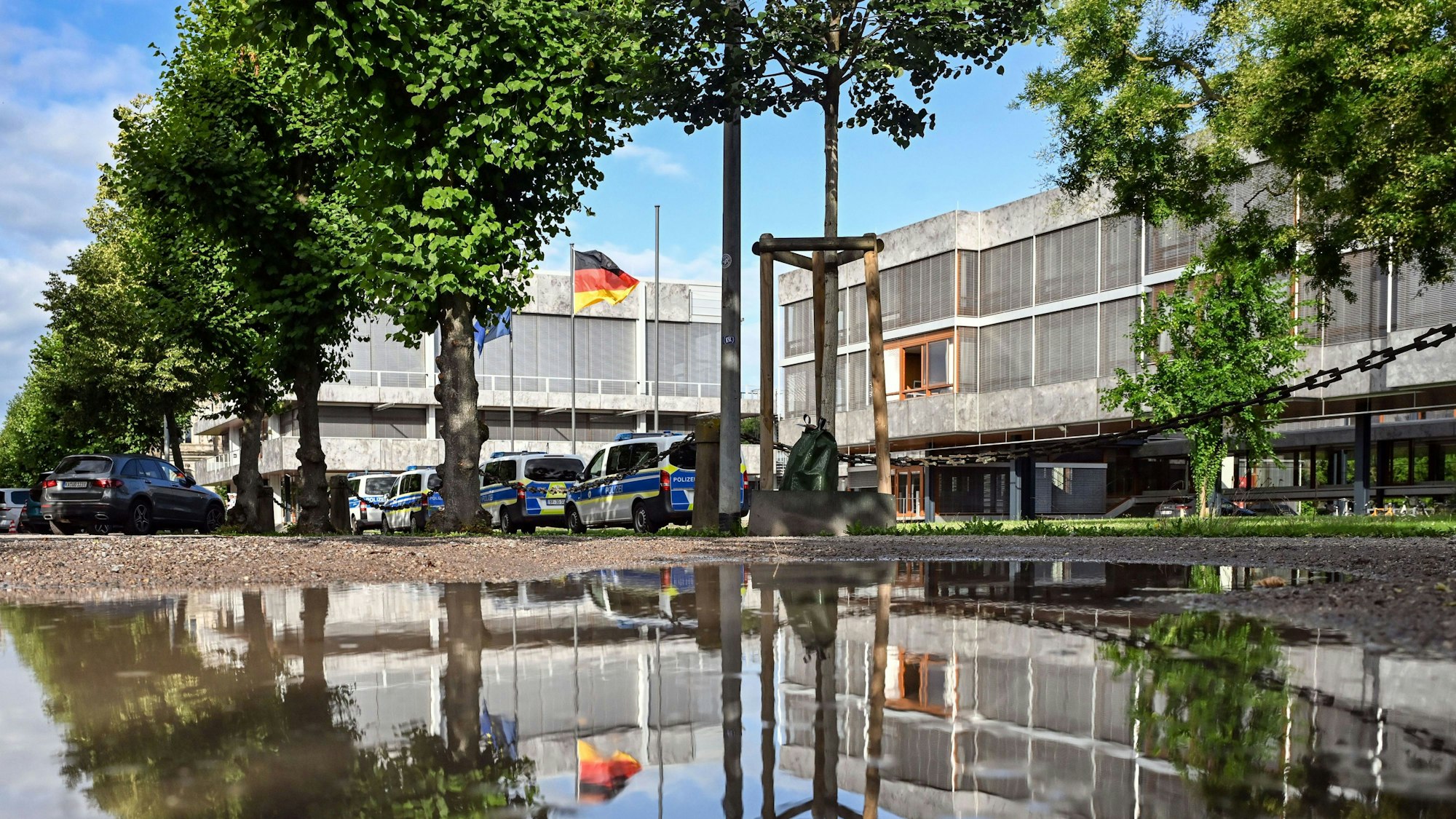 Außenaufnahme des Bundesverfassungsgerichtes, das sich in einer Pfütze spiegelt.