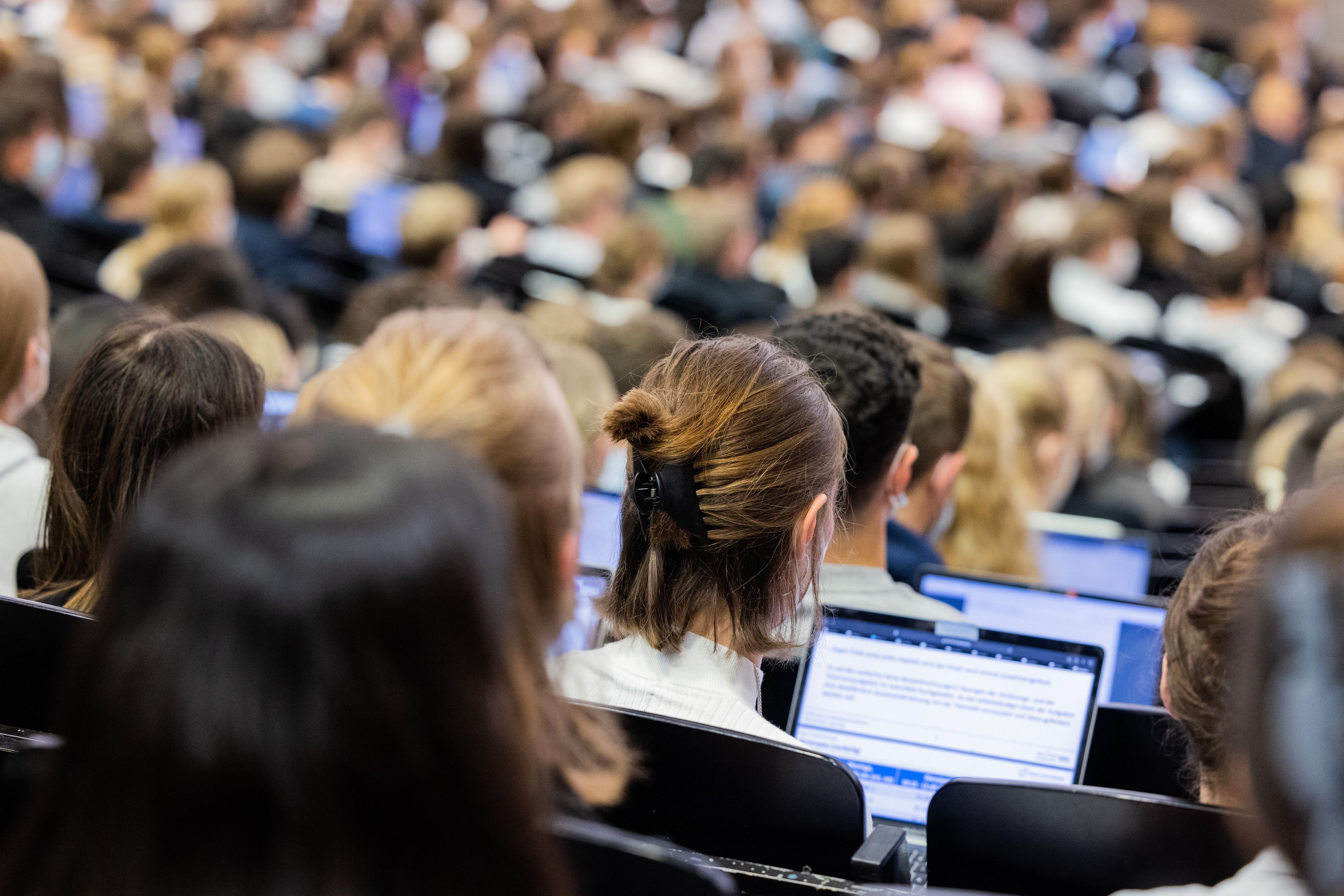 Studentinnen und Studenten sitzen während einer Vorlesung in einem Hörsaal.