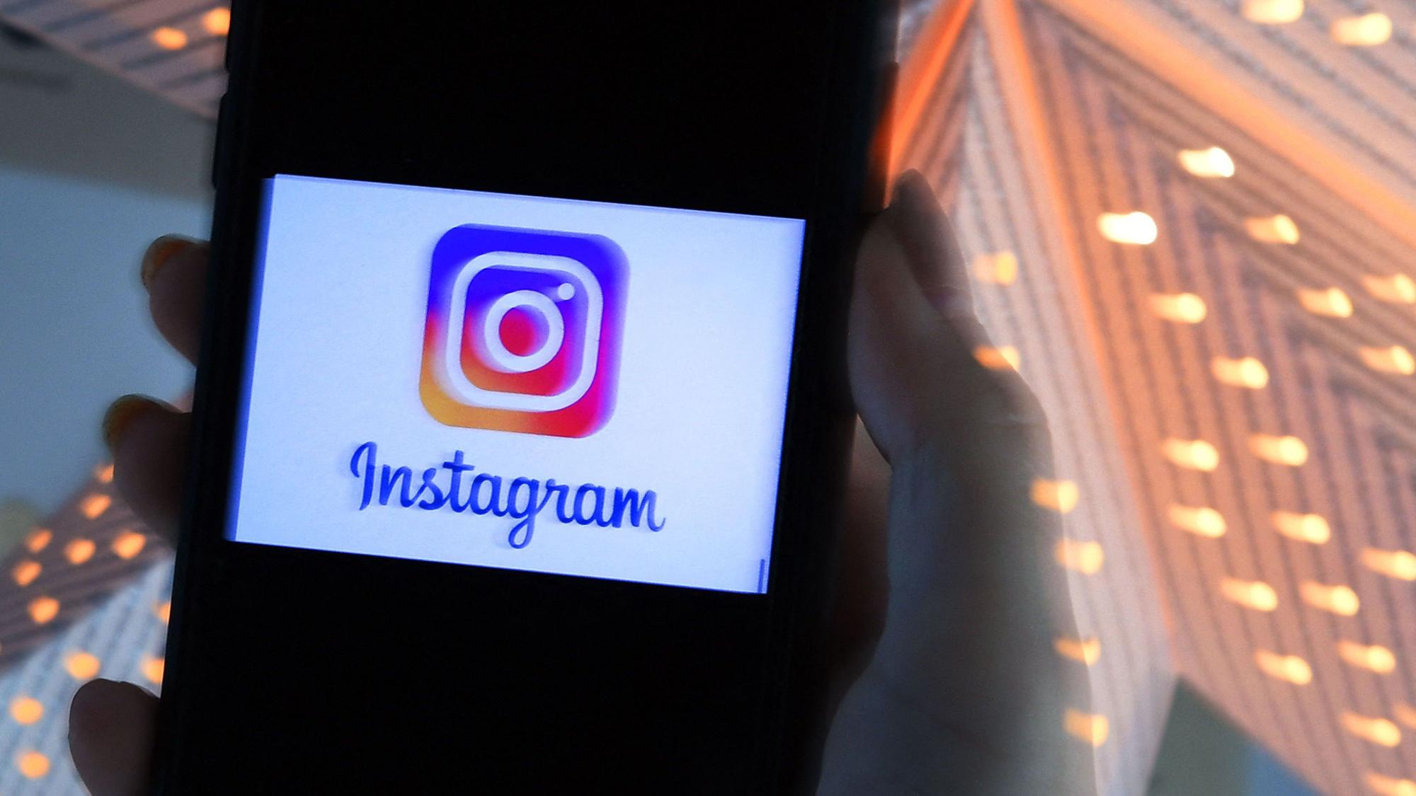 Das Logo der Meta-App Instagram leuchtet auf einem Handy-Display auf.