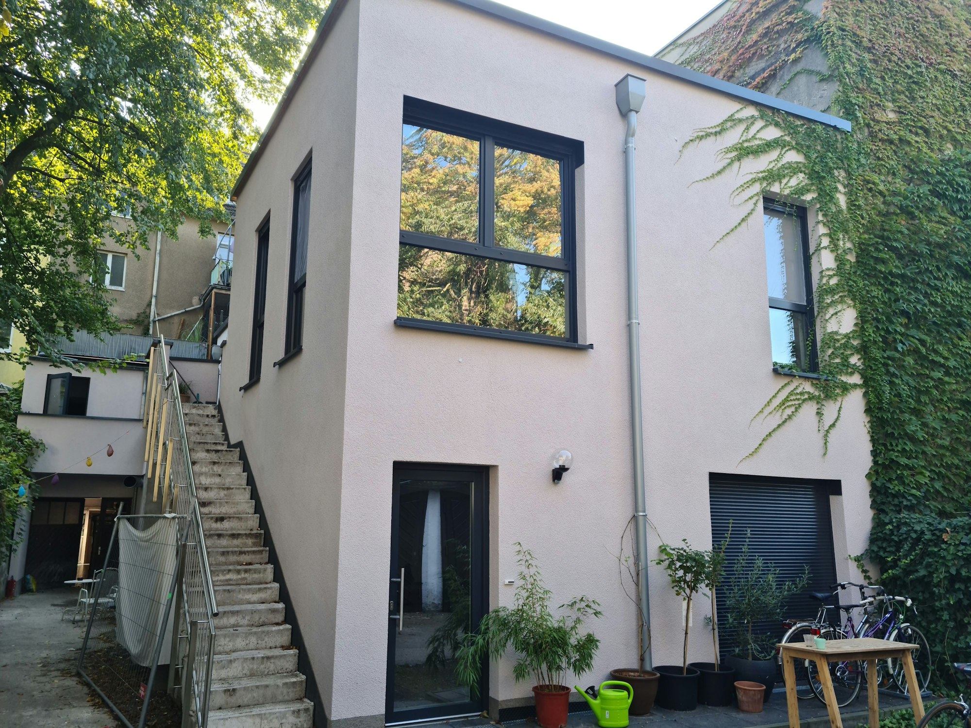 Blick auf ein Hinterhaus mit einer kleinen Terrasse davor und einer Seitentreppe