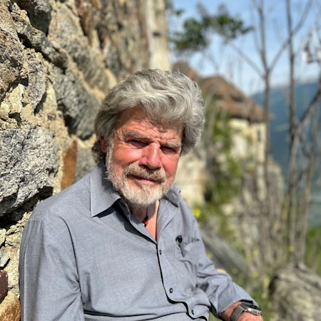 Der Bergsteiger Reinhold Messner sitzt an seinem Schloss Juval auf einer Bank.