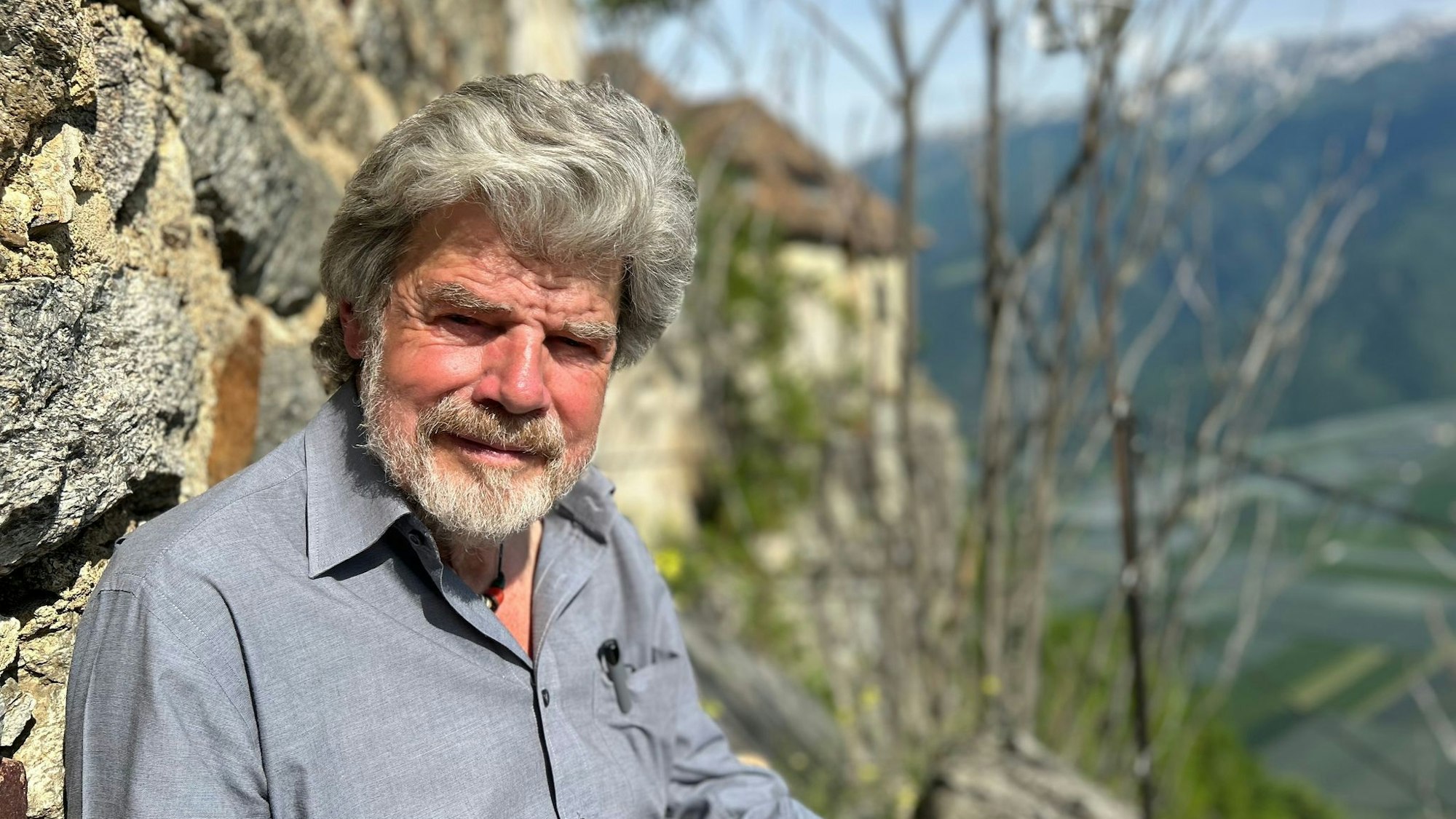 Der Bergsteiger Reinhold Messner sitzt an seinem Schloss Juval auf einer Bank.