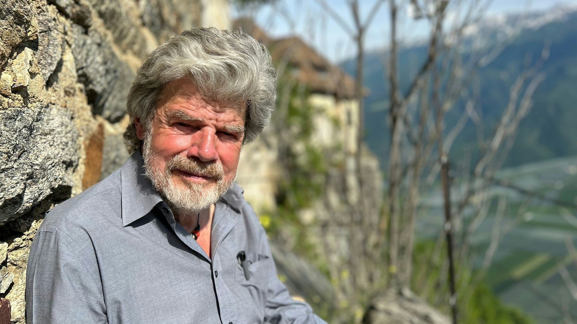 Der Bergsteiger Reinhold Messner sitzt an seinem Schloss Juval auf einer Bank.