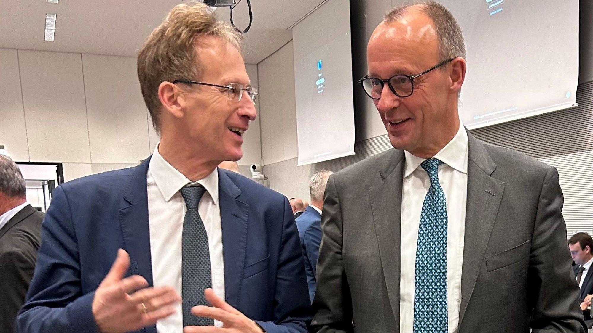 Zwei Männer in Anzügen, Detlef Seif und Friedrich Merz, unterhalten sich.