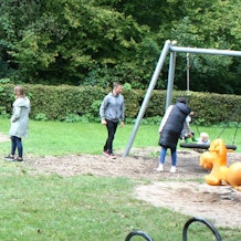 Ein Spielplatz mit Kindern, Erwachsenen, Schaukeln und Klettergerüsten.