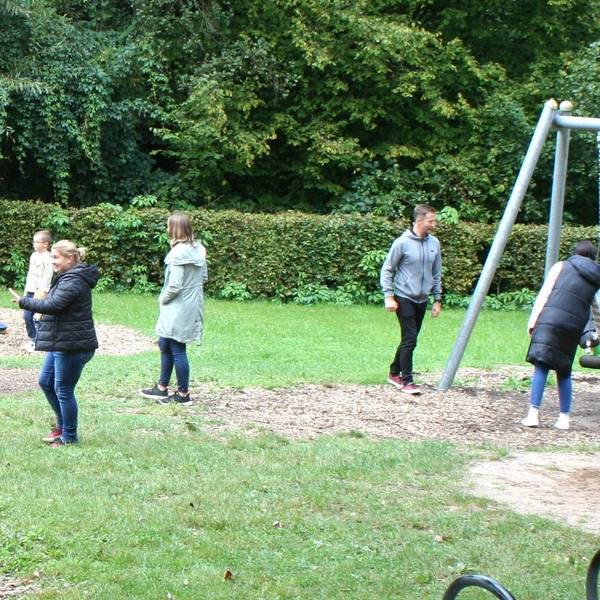 Ein Spielplatz mit Kindern, Erwachsenen, Schaukeln und Klettergerüsten.