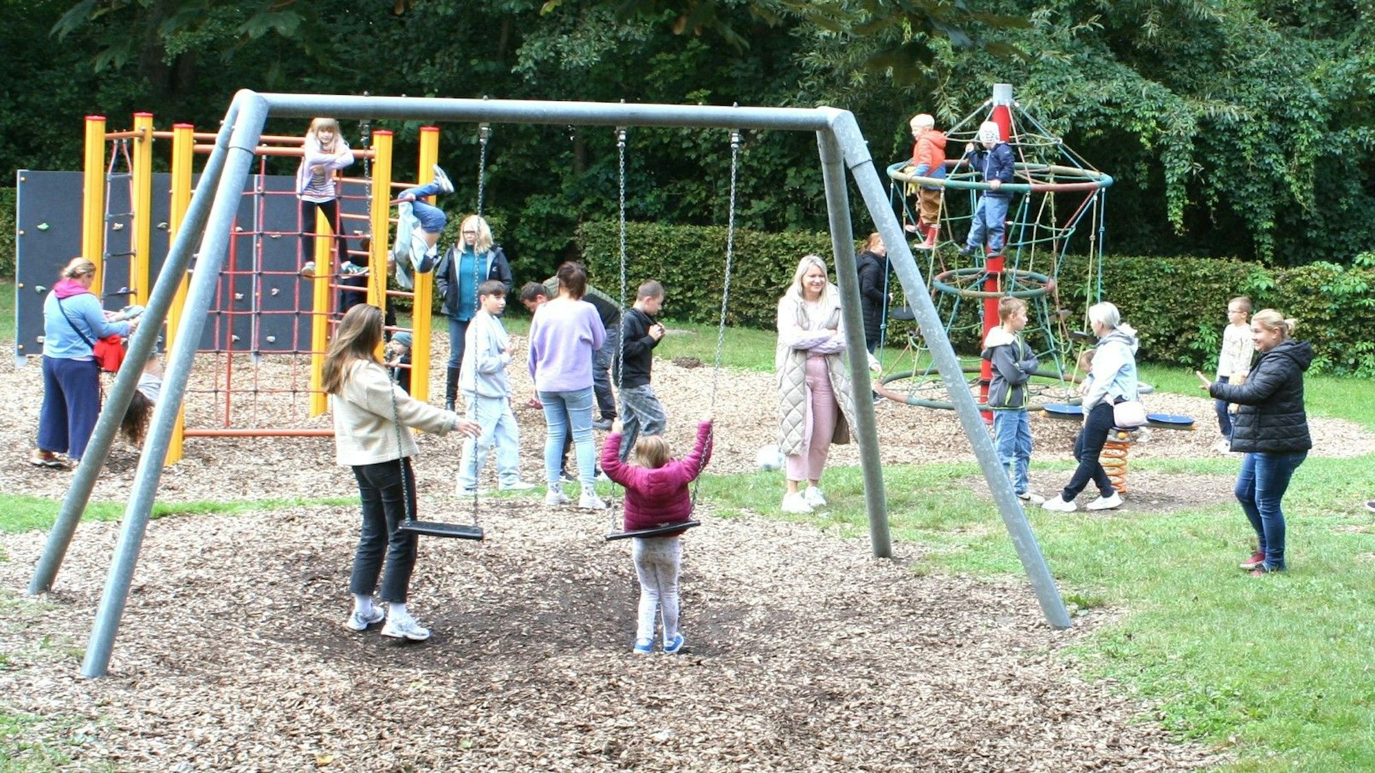 Kinder spielen an den Geräten auf einem Spielplatz.