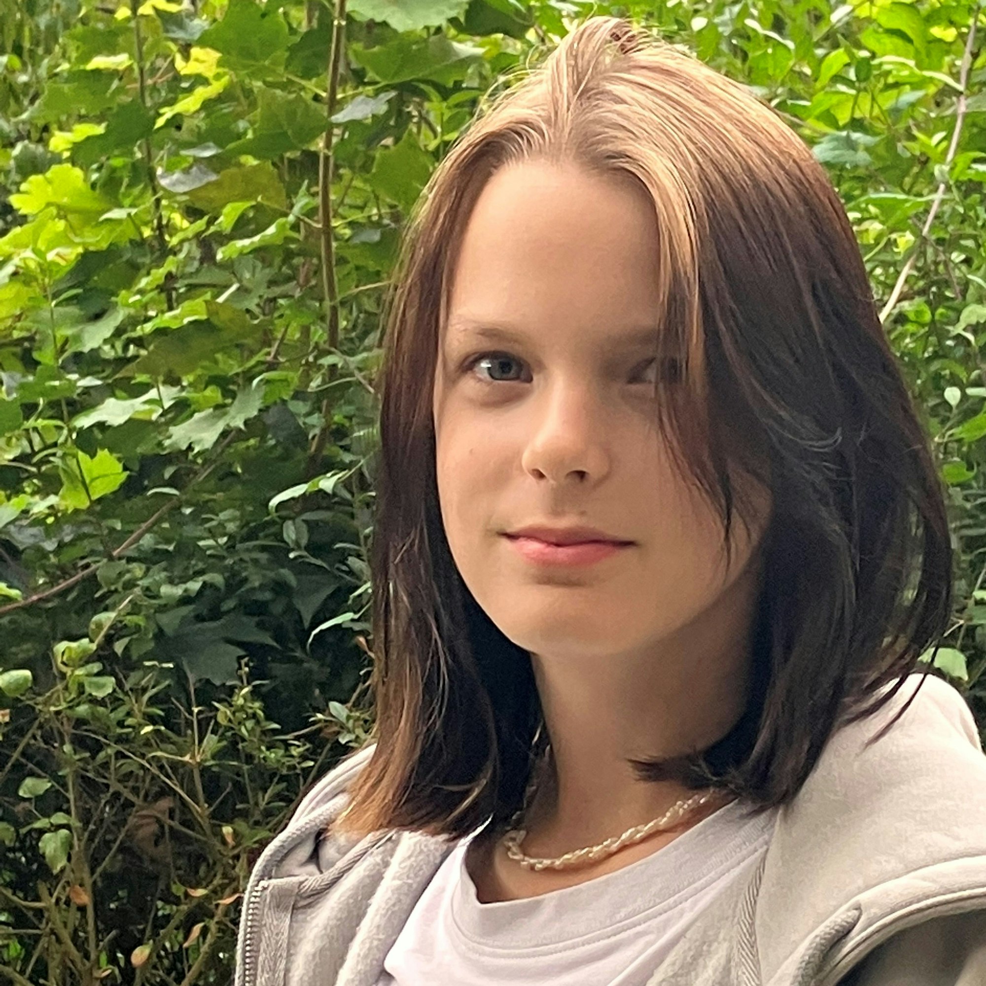 Annika schaut in die Kamera. Sie hat schulterlanges mittelbraunes Haar und trägt eine beige Sweatshirtjacke.