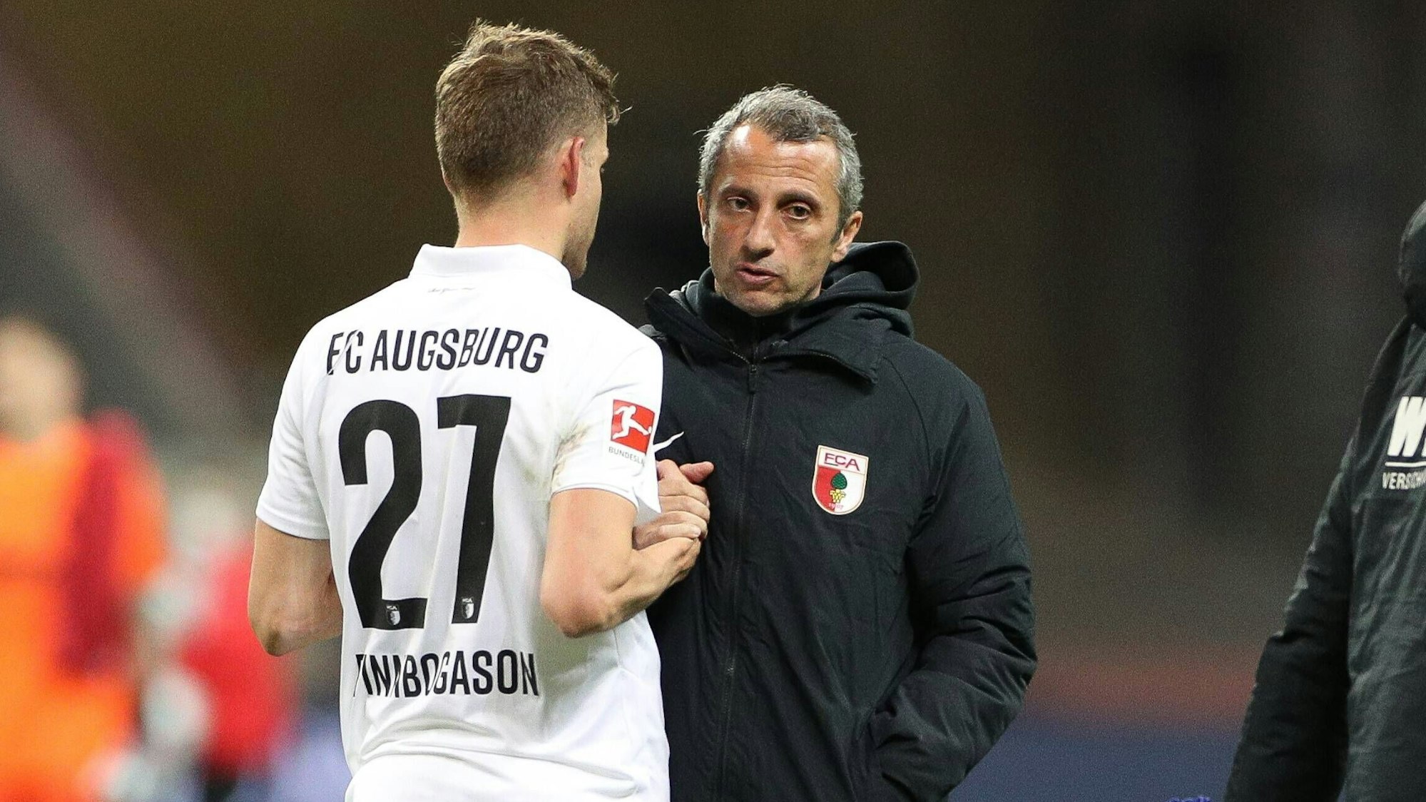 Auf dem Spielfeld spricht Iraklis Metaxas mit dem Augsburger Fußballer Alfred Finnbogason.