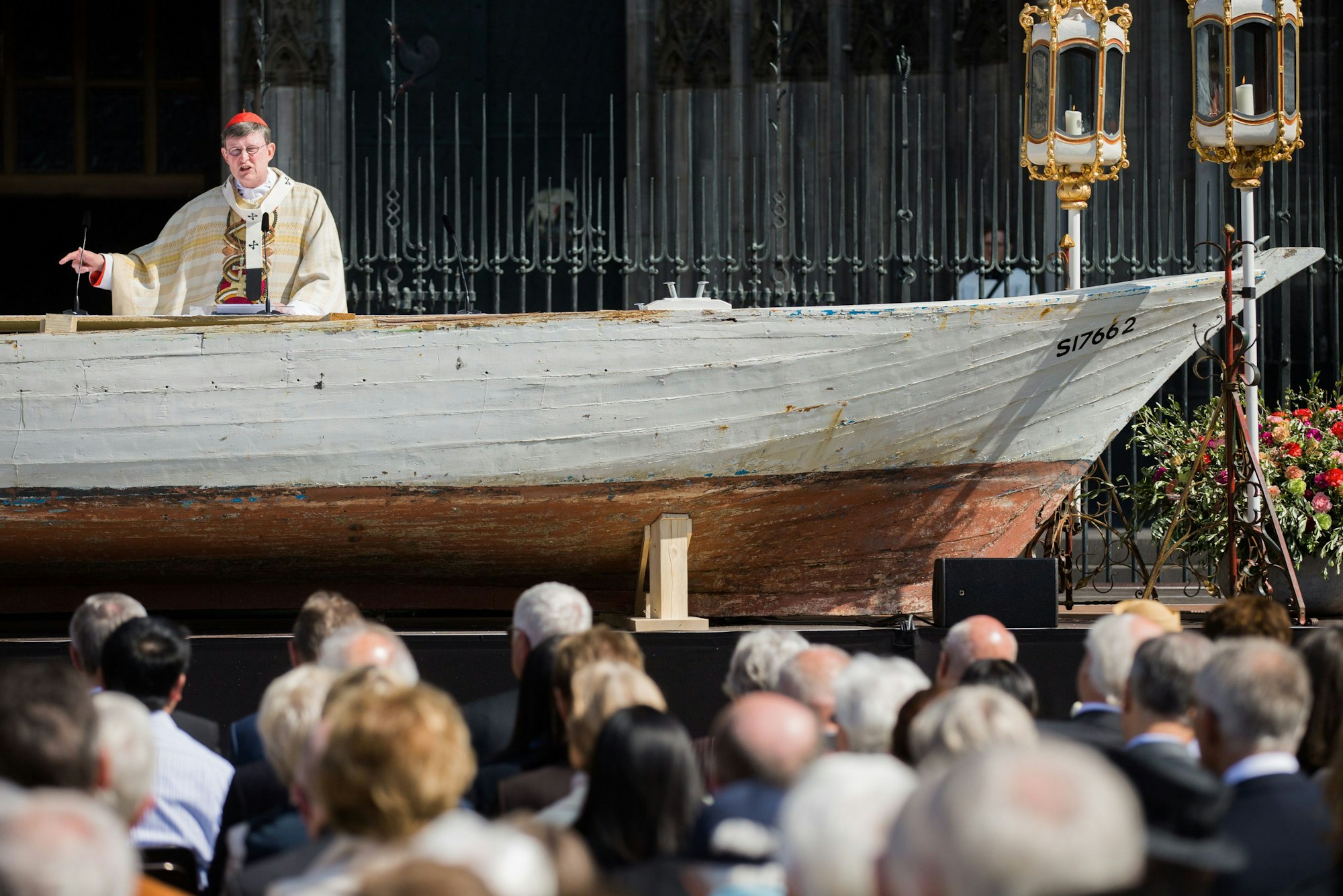 ARCHIV - Kardinal Rainer Woelki feiert am 26.05.2016 auf dem Roncalliplatz vor dem Dom in Köln (Nordrhein-Westfalen) an einem Flüchtlingsboot, das als Altar dient, eine Fronleichnamsmesse. (Archivbild)