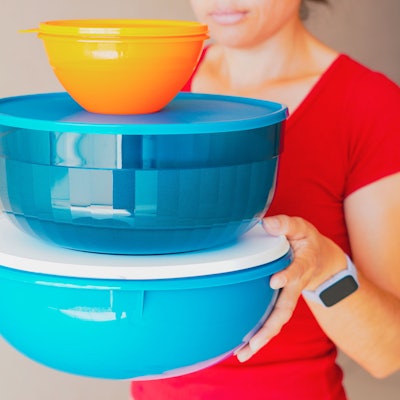 Eine Frau trägt luftdicht verschließbare Behälter von Tupperware.