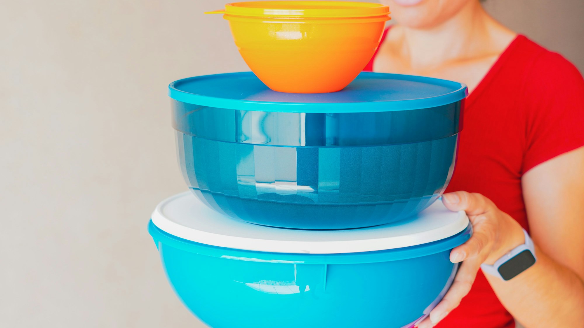 Eine Frau trägt luftdicht verschließbare Behälter von Tupperware.