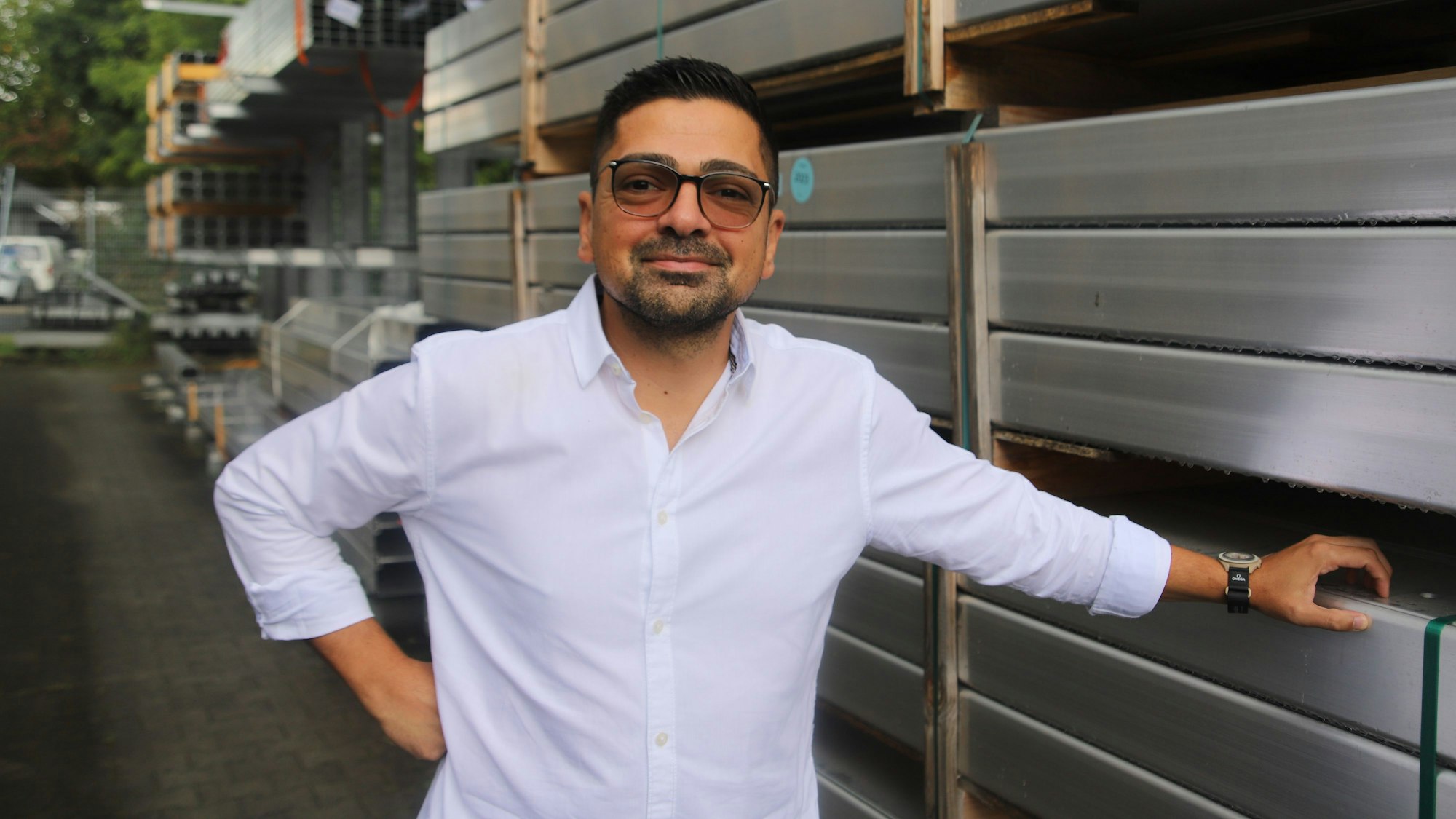 Ein Mann mit Brille steht vor Aluminiumprofilen.
