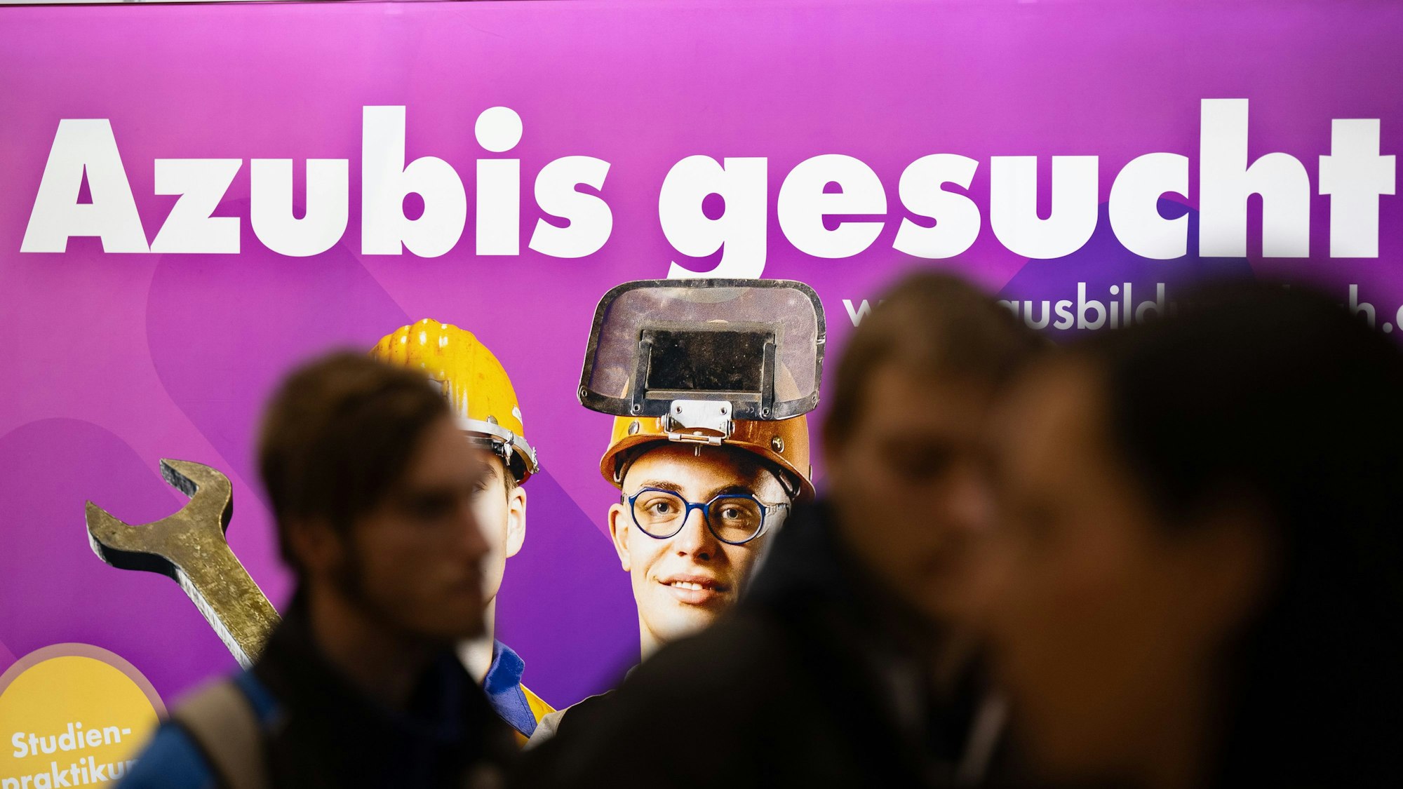 Besucher stehen auf der Jobmesse „KarriereStart“ vor dem Schriftzug „Azubis gesucht“