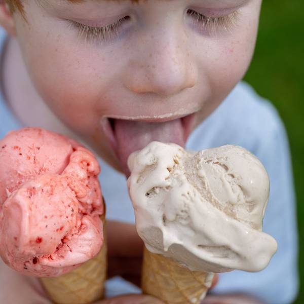 Ein Kleinkind leckt bei sommerlichen Temperaturen an einem Eis in der Waffel.