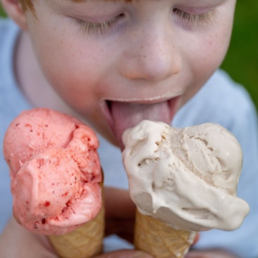 Ein Kleinkind leckt bei sommerlichen Temperaturen an einem Eis in der Waffel.