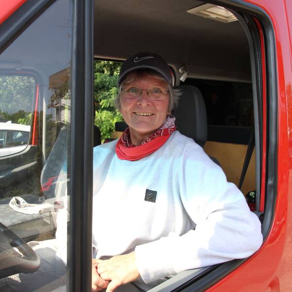 Eine Frau am Steuer eines roten Transporters