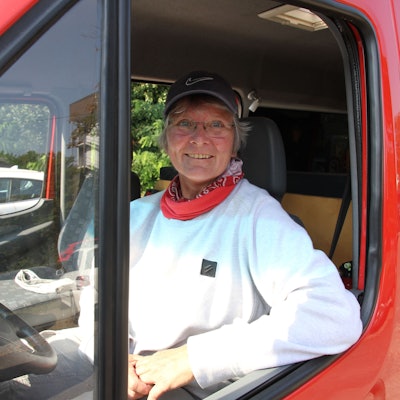 Eine Frau am Steuer eines roten Transporters