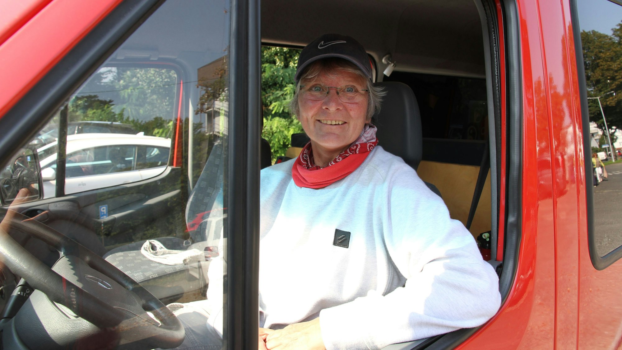 Eine Frau am Steuer eines roten Transporters