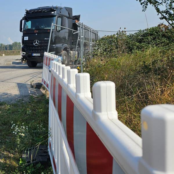 Ein Lastwagen verlässt eine mit Zäunen geschützte Baustelle.