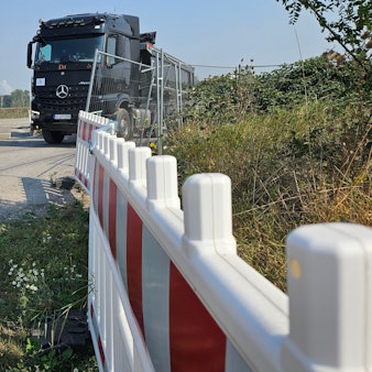 Ein Lastwagen verlässt eine mit Zäunen geschützte Baustelle.