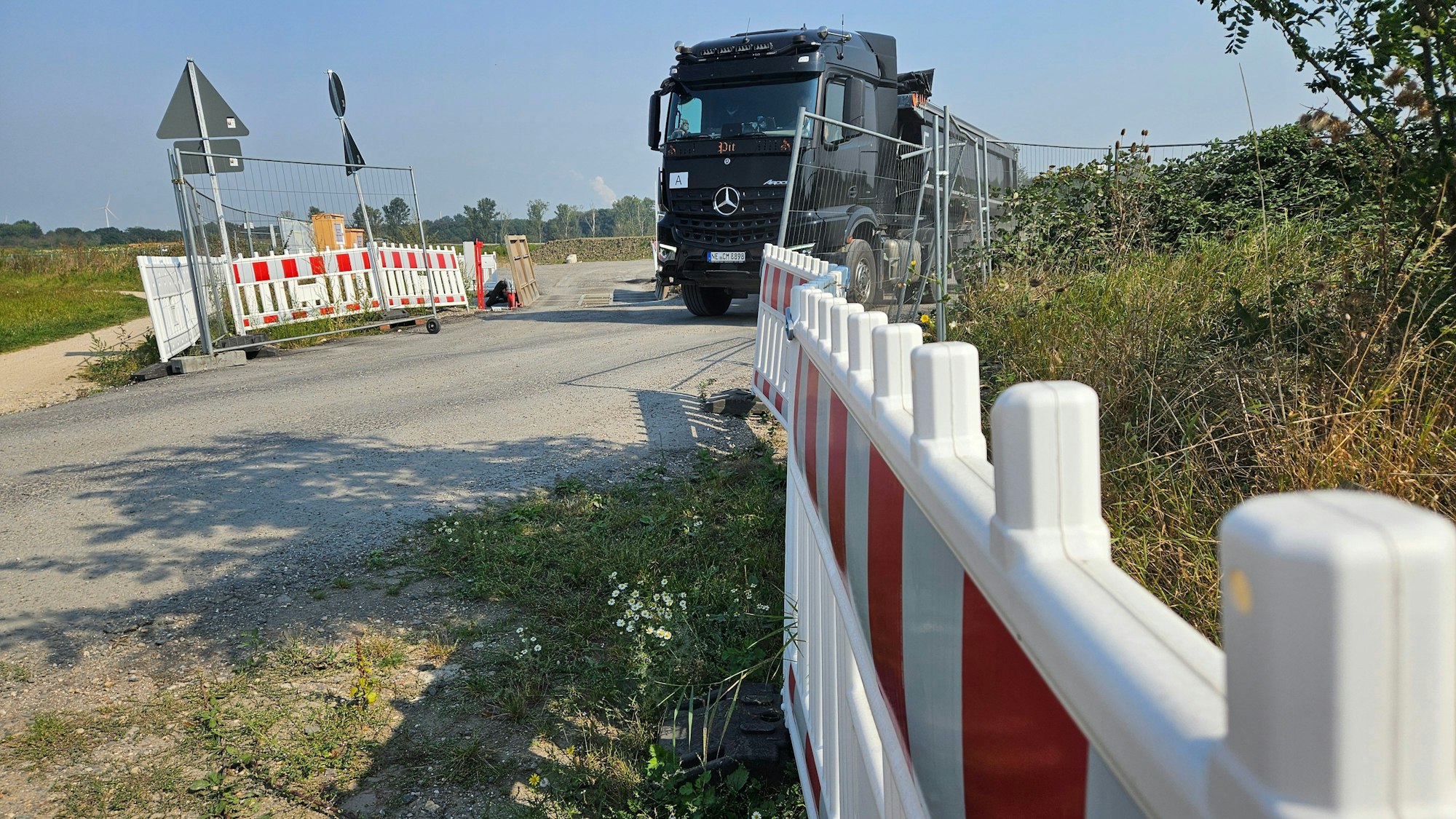Ein Lastwagen verlässt eine mit Zäunen geschützte Baustelle.
