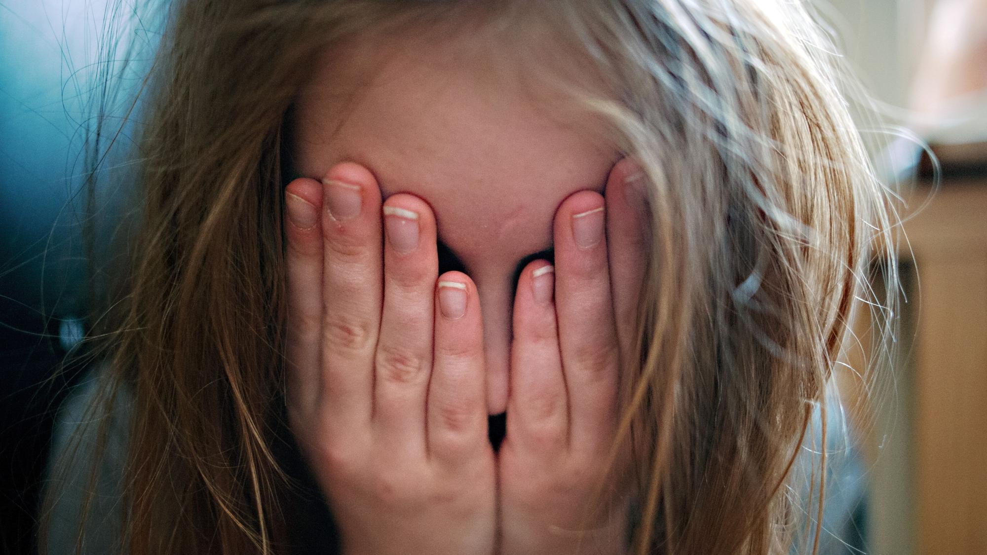 Ein junges Mädchen hält sich die Hände vor ihr Gesicht.Nordrhein-westfälische Kindertagesstätten sollen sicher sein für Kinder - in immer mehr werdenden Fällen sind sie dies jedoch nicht.
