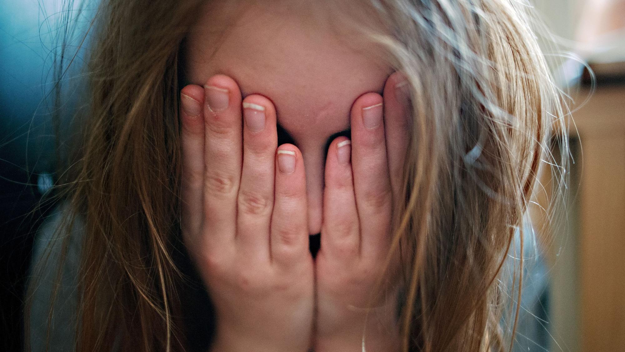 ILLUSTRATION - Ein junges Mädchen hält sich die Hände vor ihr Gesicht. Die Hinweise auf Kindeswohlgefährdung in Rheinland-Pfalz haben im vergangenen Jahr um 5,6 Prozent zugenommen. (zu dpa «Sorge ums Kindeswohl - Jugendämter gehen mehr als 8700 Meldungen nach») +++ dpa-Bildfunk +++