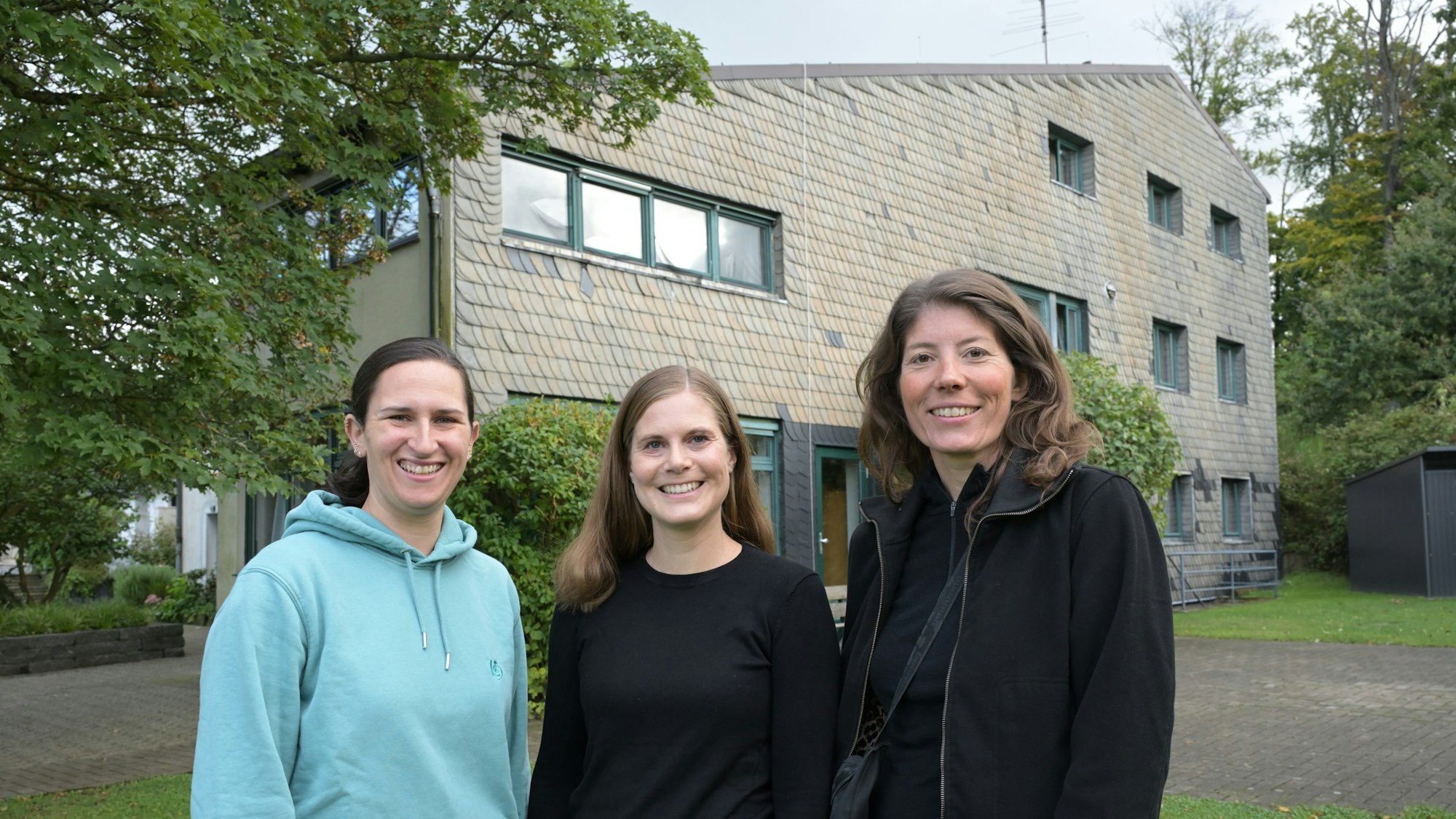 Drei Frauen stehen vor einem Haus.