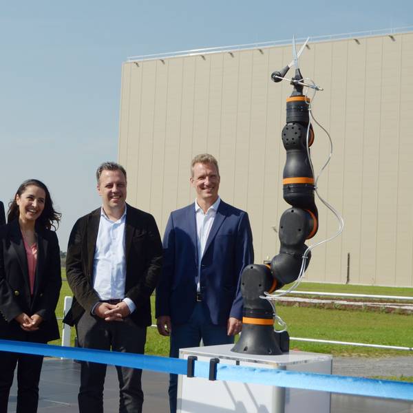 Vertreter des Unternehmens Procter & Gamble und Gäste stehen hinter einem blauen Band. Sie beobachten, wie ein Roboter eine Schere in Position bringt, die das Band durchtrennen soll.