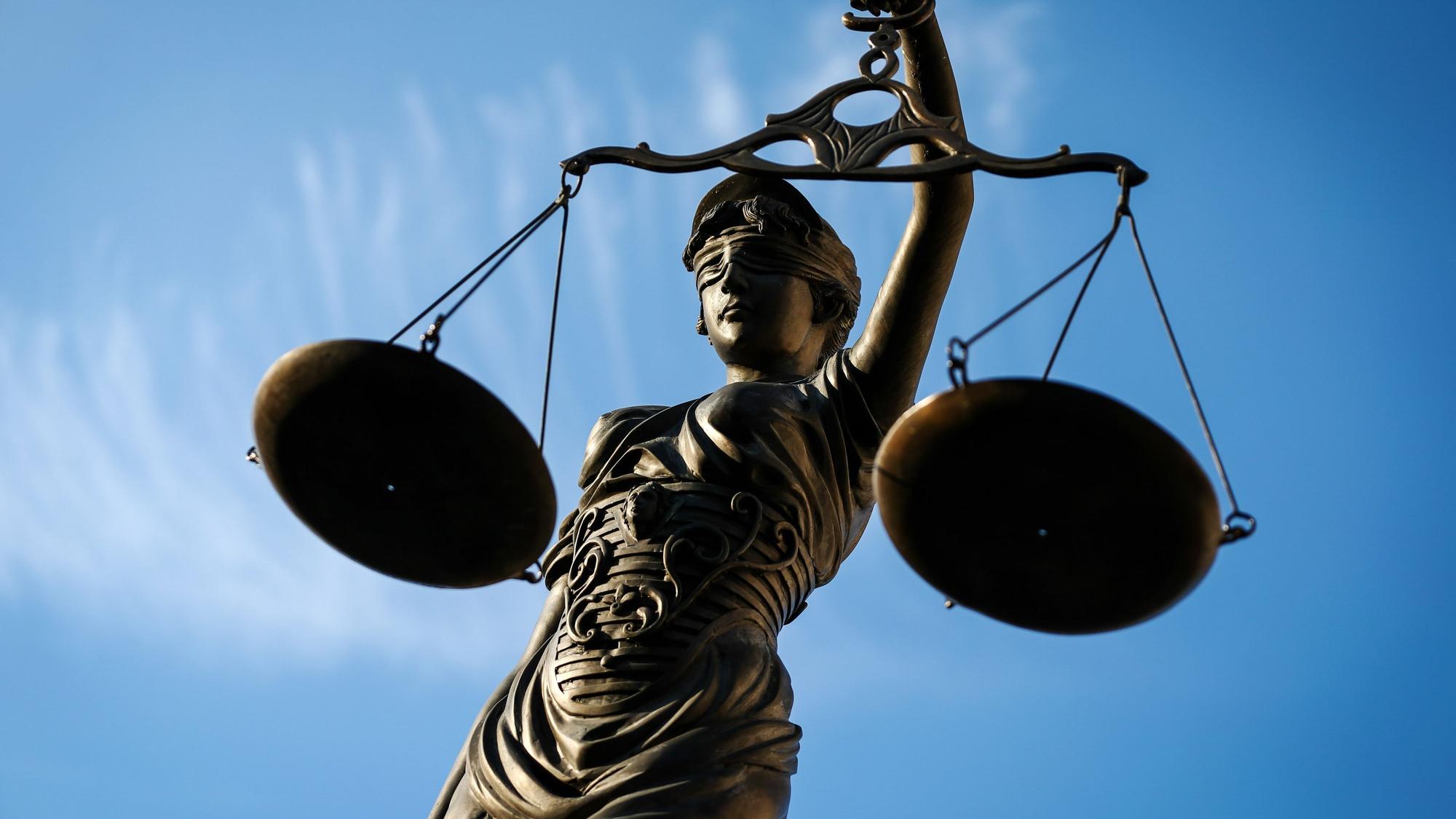 Eine Statue der Justitia hält eine Waage in der Hand.