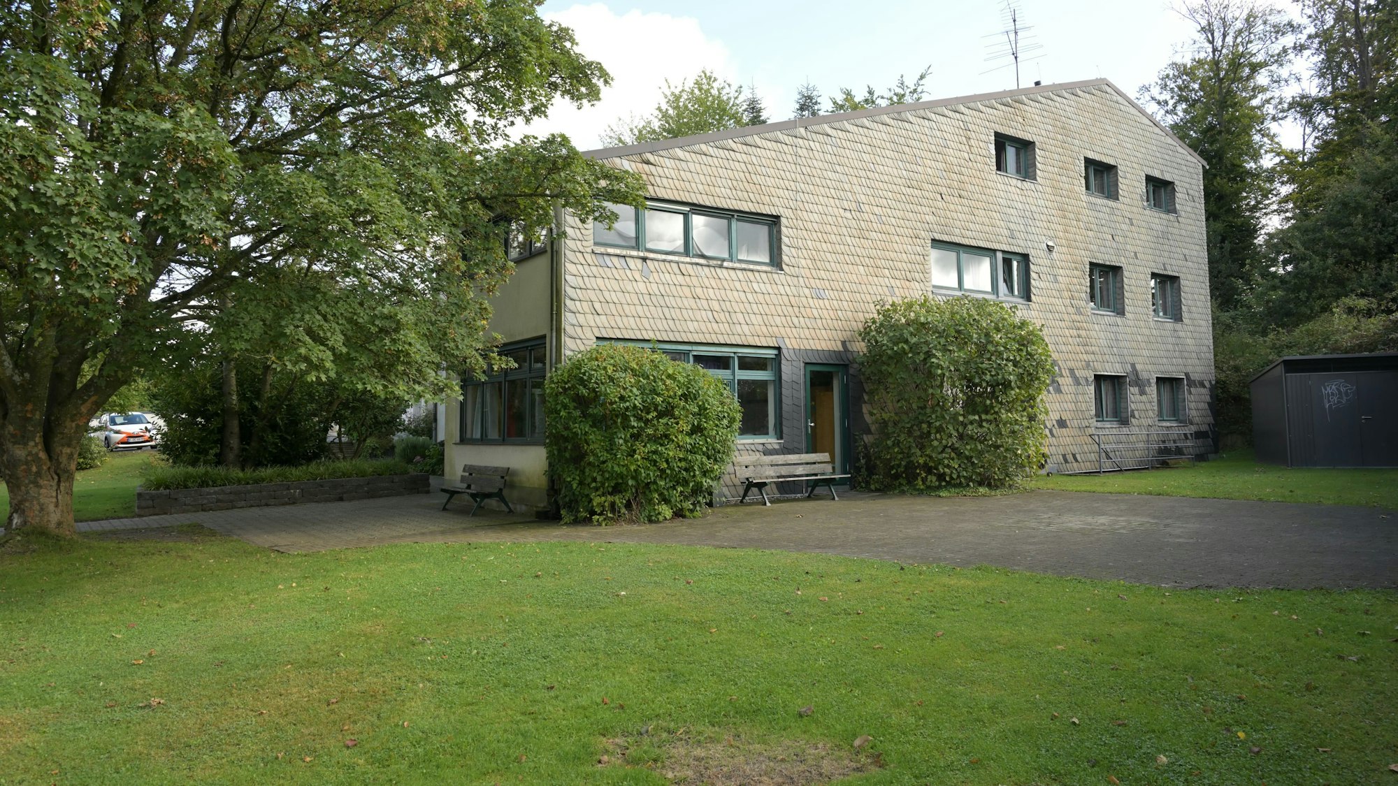 Ein Gebäude in einem großen Garten mit Wiese.