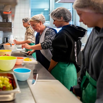 Das Bild zeigt drei Schüler der Stephanus-Schule in Bürvenich beim Schnippeln in der Schulküche. Unterstützt werden sie von einer Lehrerin.