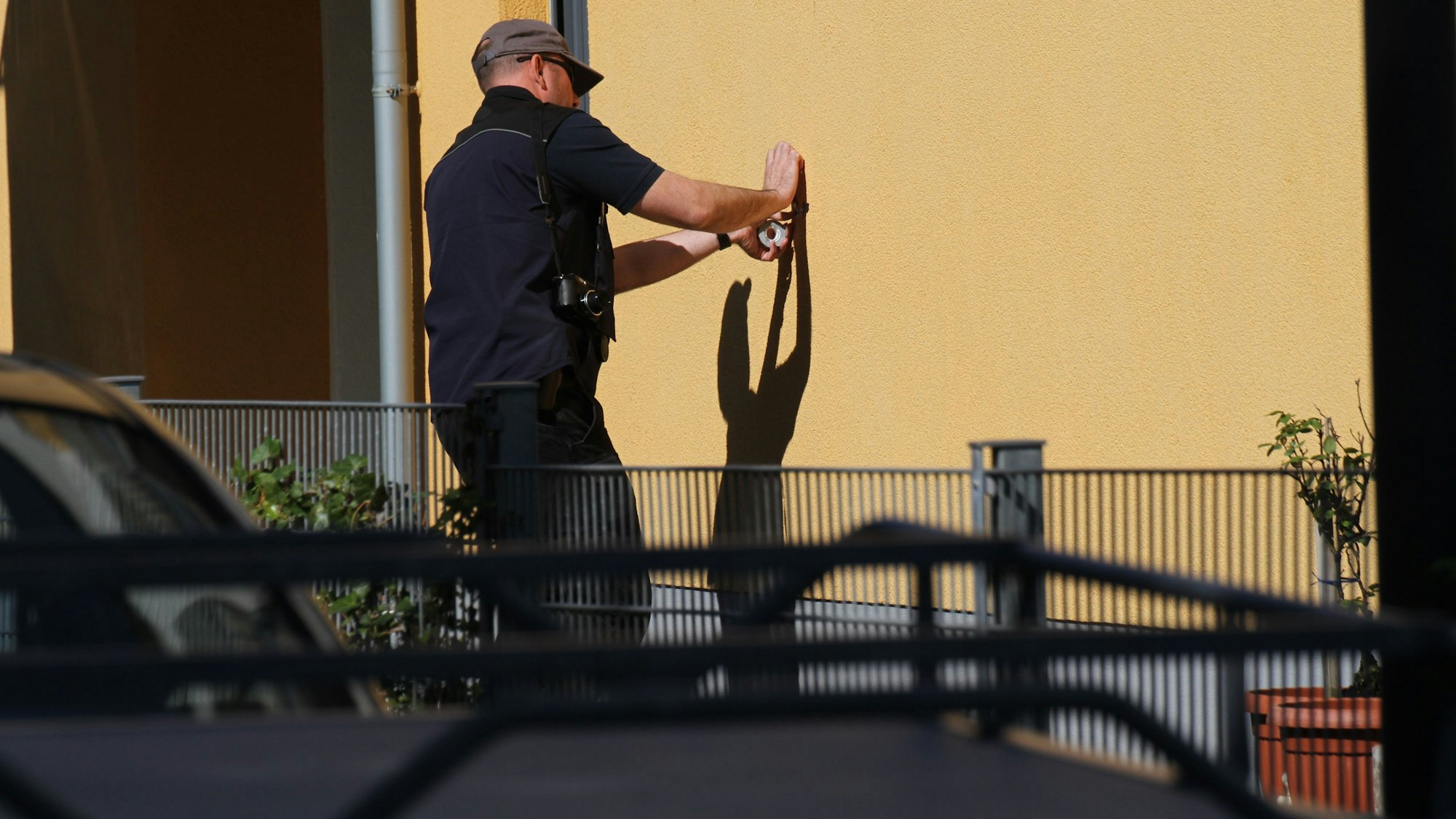 Ein Ermittler zieht ein Projektil aus einer Hauswand am Tatort.