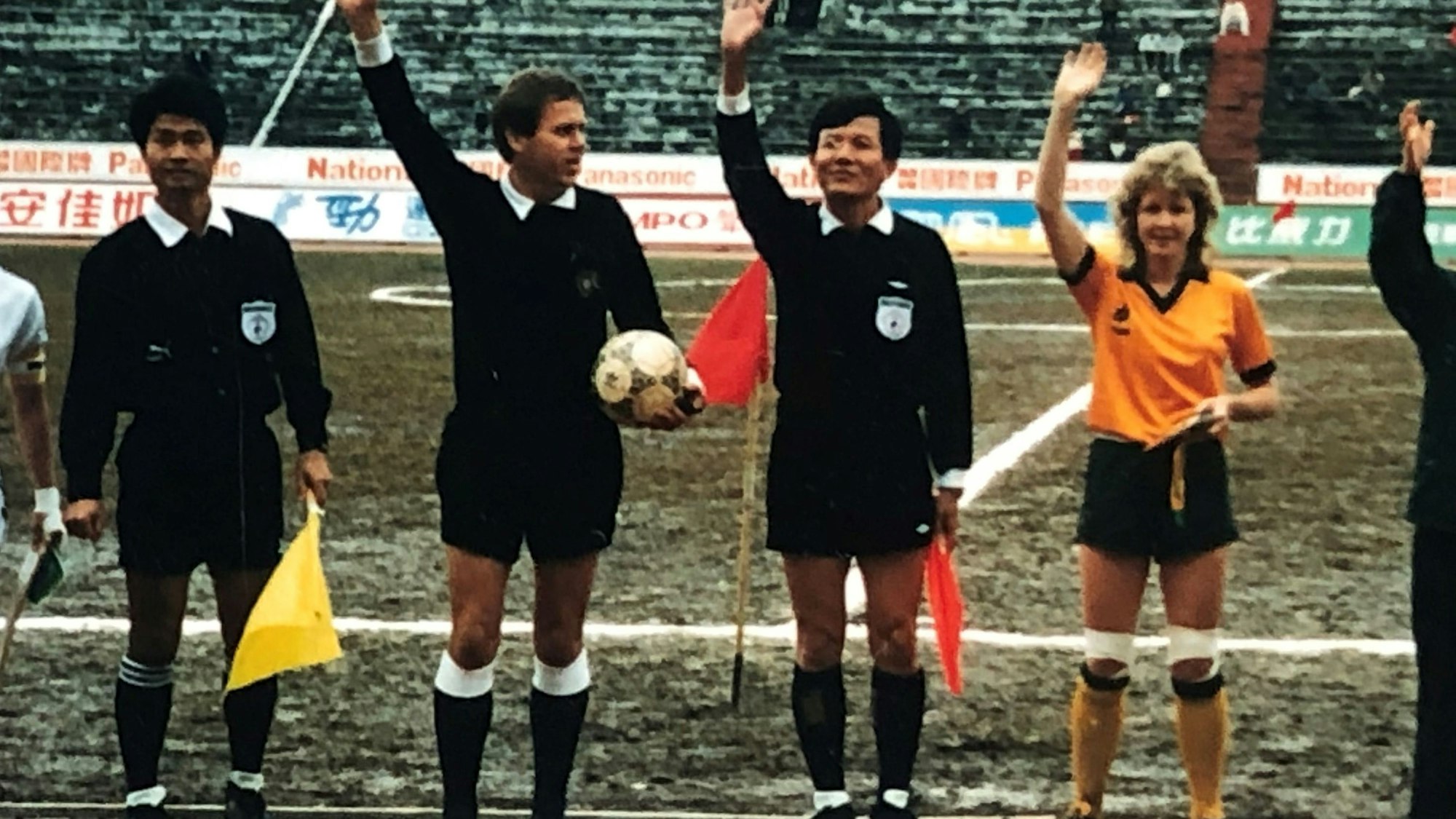 Drei Schiedsrichter und eine Fußballerin in einem gelben Trikot