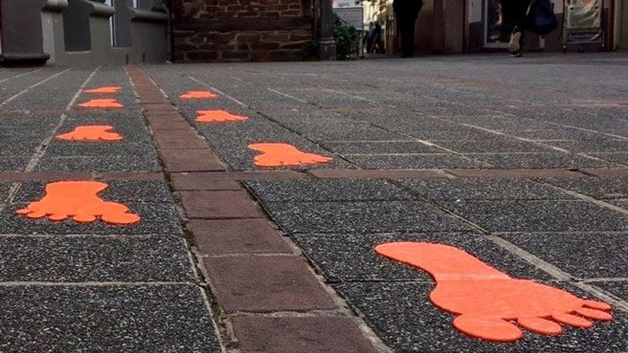 Das Bild zeigt im Rahmen des Projekts "Bespielbare Stadt" farbige Fußspuren auf dem Pflaster der Kirchstraße in Brühl.