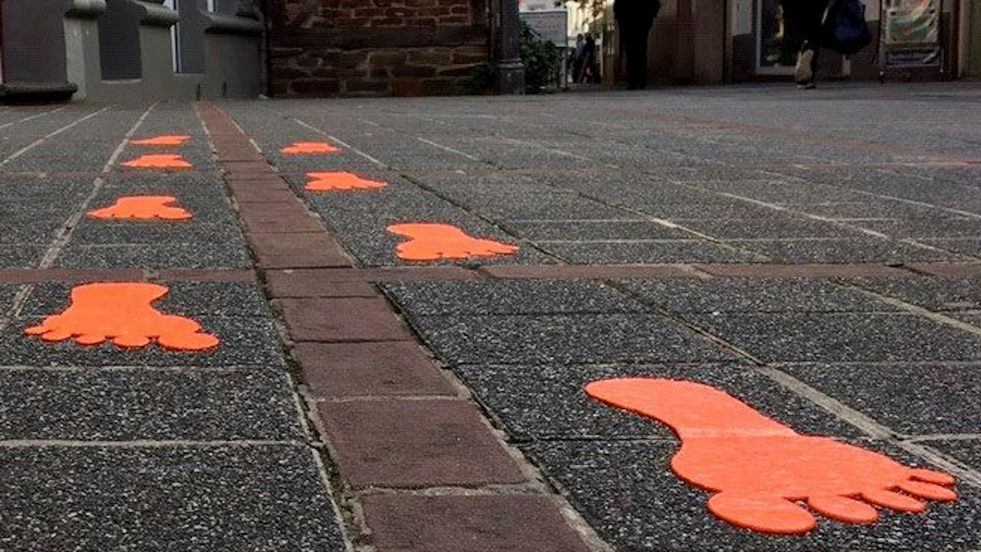 Das Bild zeigt im Rahmen des Projekts "Bespielbare Stadt" farbige Fußspuren auf dem Pflaster der Kirchstraße in Brühl.