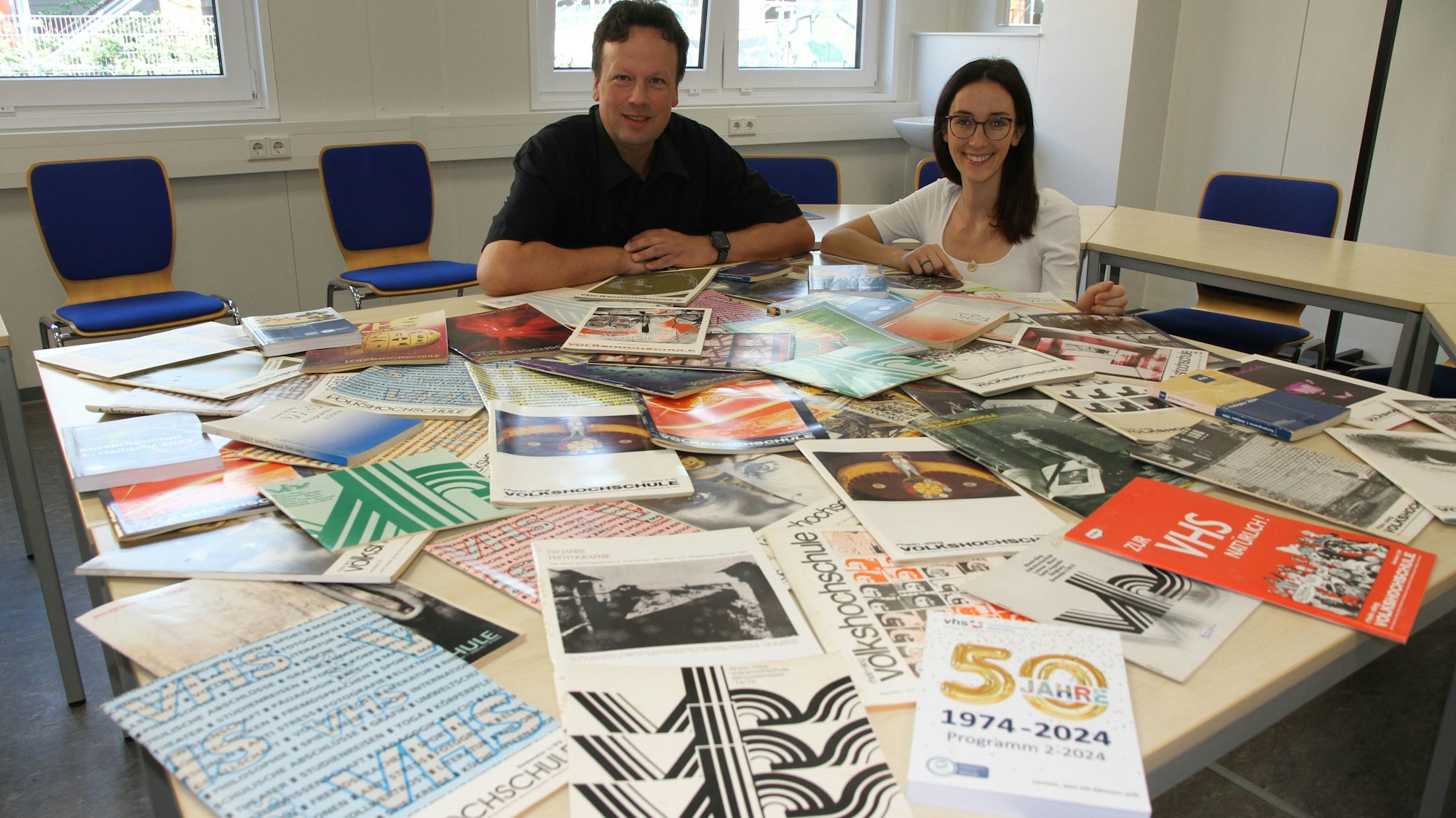 Ein Mann und eine Frau hinter einem Tisch voller Broschüren
