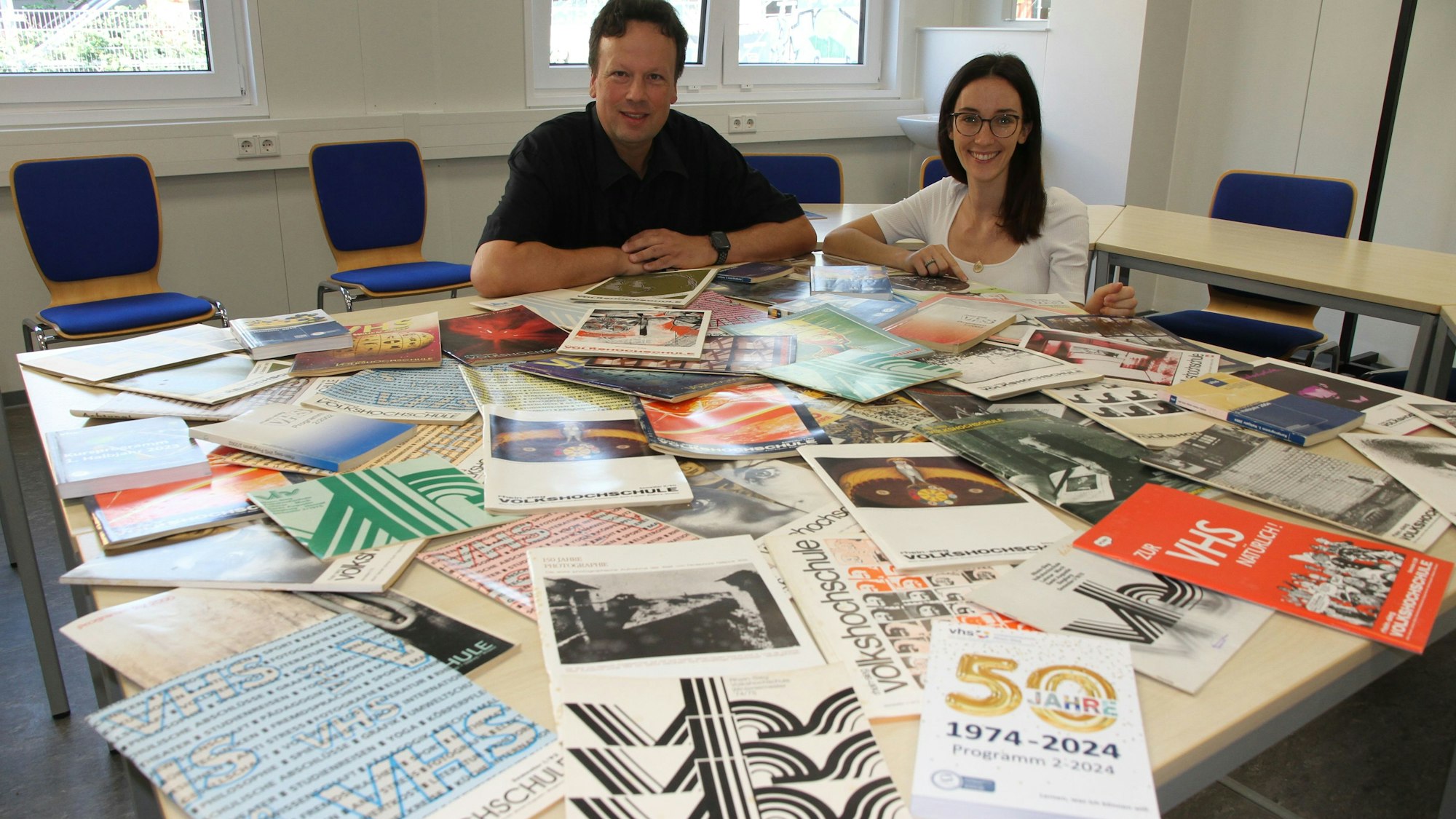 50 Jahre VHS, 100 Programmhefte, Leiter Holger Hansen und Jenny Kowalczyk, zuständig für Digitale Bildung und Kommunikation