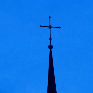 Das Kreuz einer evangelisch-lutherischen Kirche ist in der Abenddämmerung zu sehen. (Symbolbild)