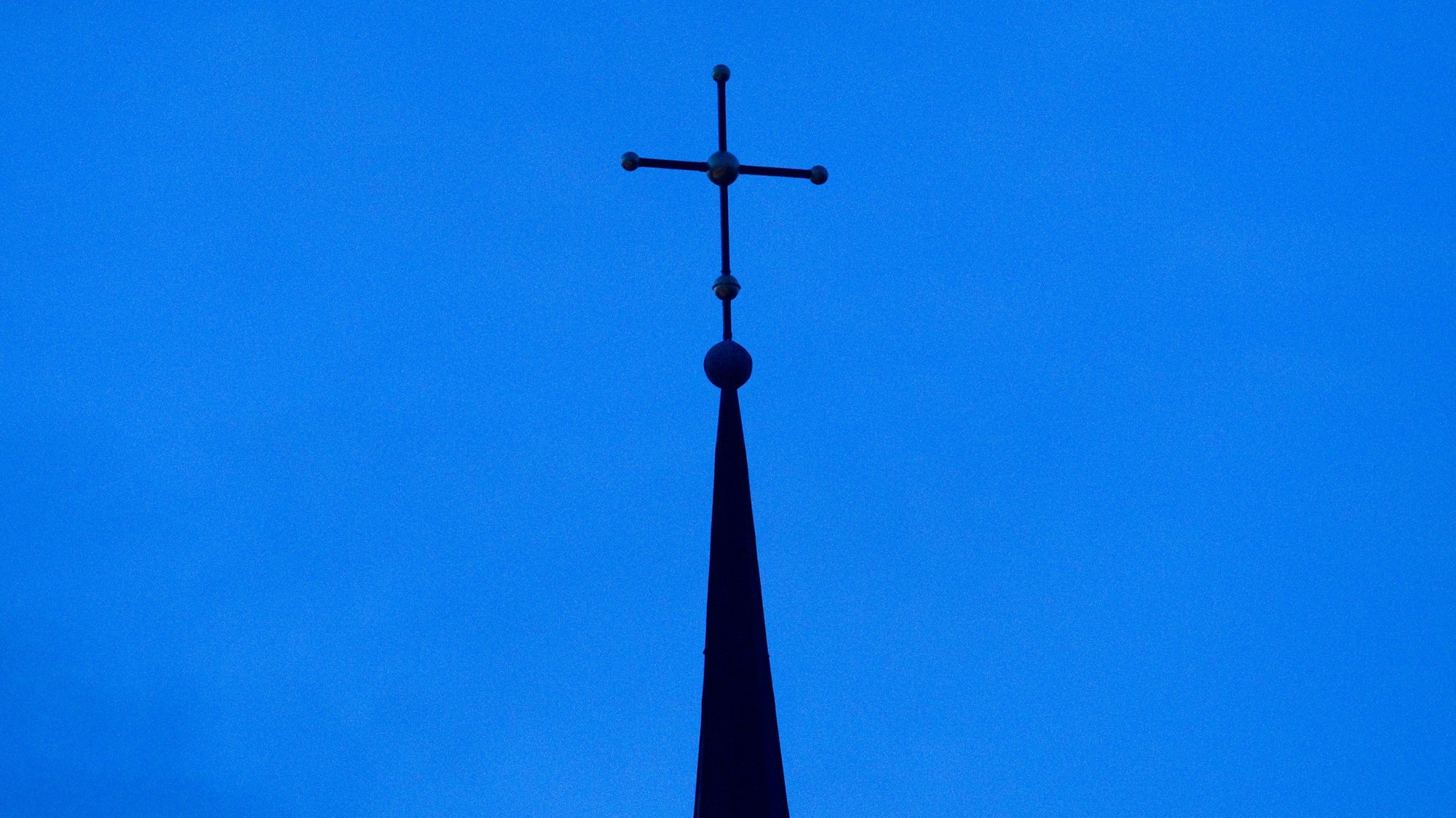 Das Kreuz einer evangelisch-lutherischen Kirche ist in der Abenddämmerung zu sehen. (Symbolbild)