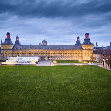 Das Hauptgebäude der Universität Bonn. Die vier Türme leuchten.